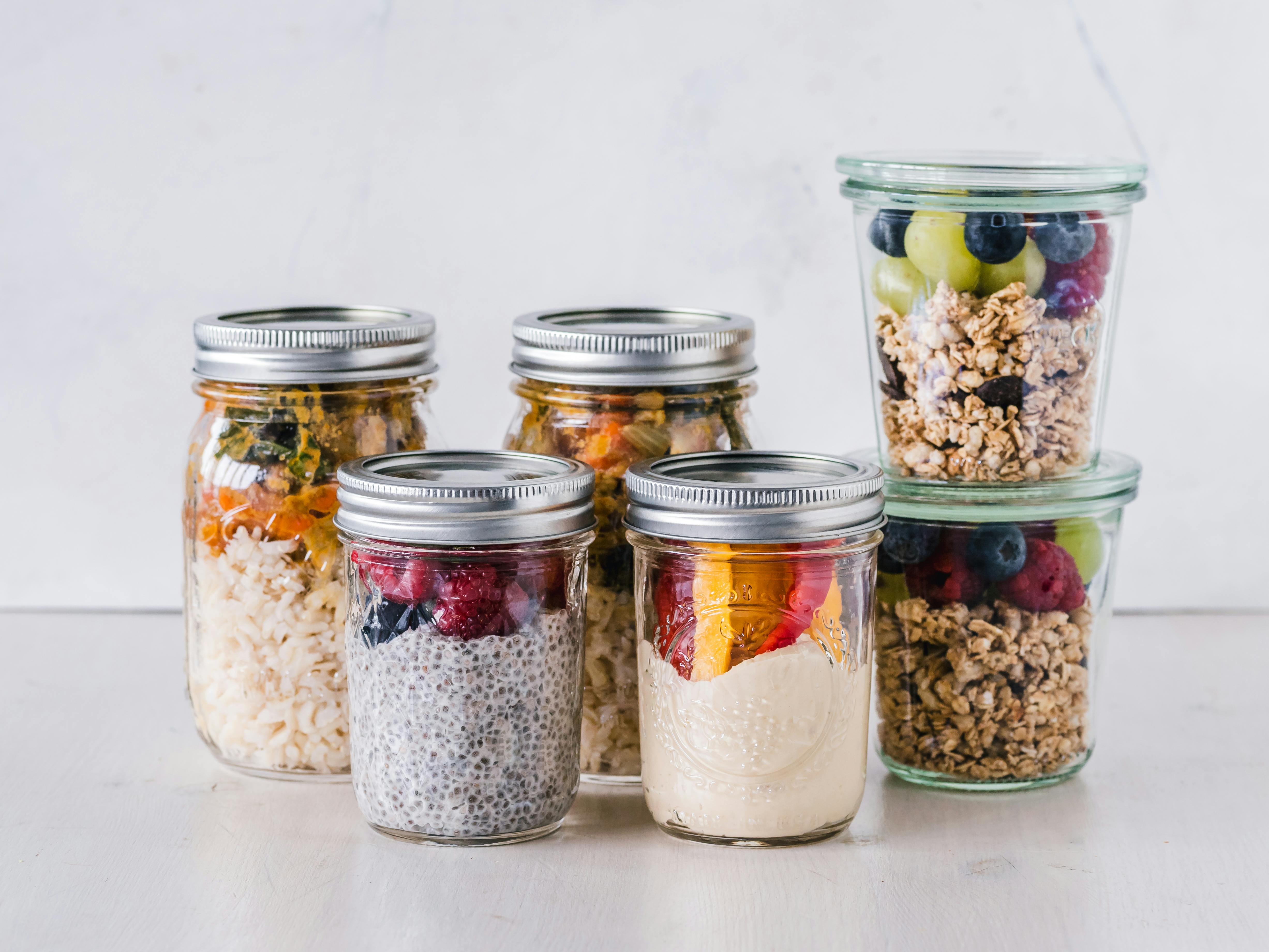 multiple jars filled with premade oatmeals, yogurts and chia puddings